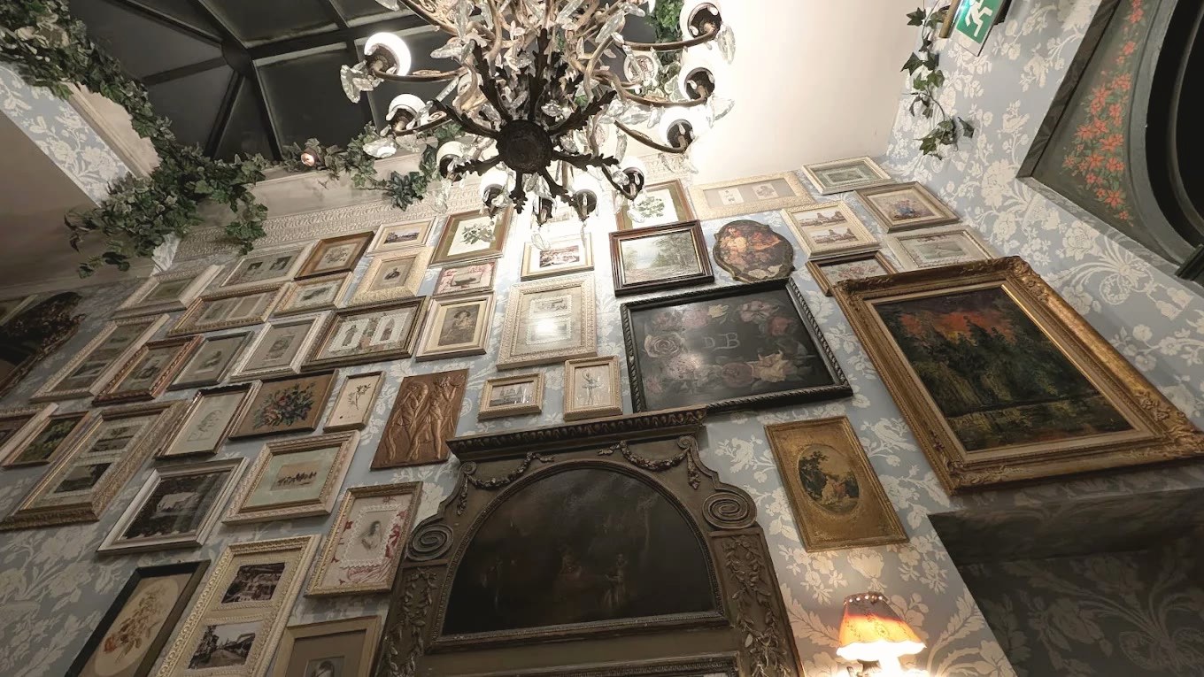 A wall covered in framed pictures beneath a crystal chandelier