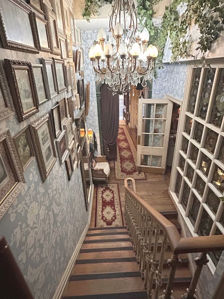 The staircase at Mari Vanna — walls of framed pictures, a chandelier and a red runner