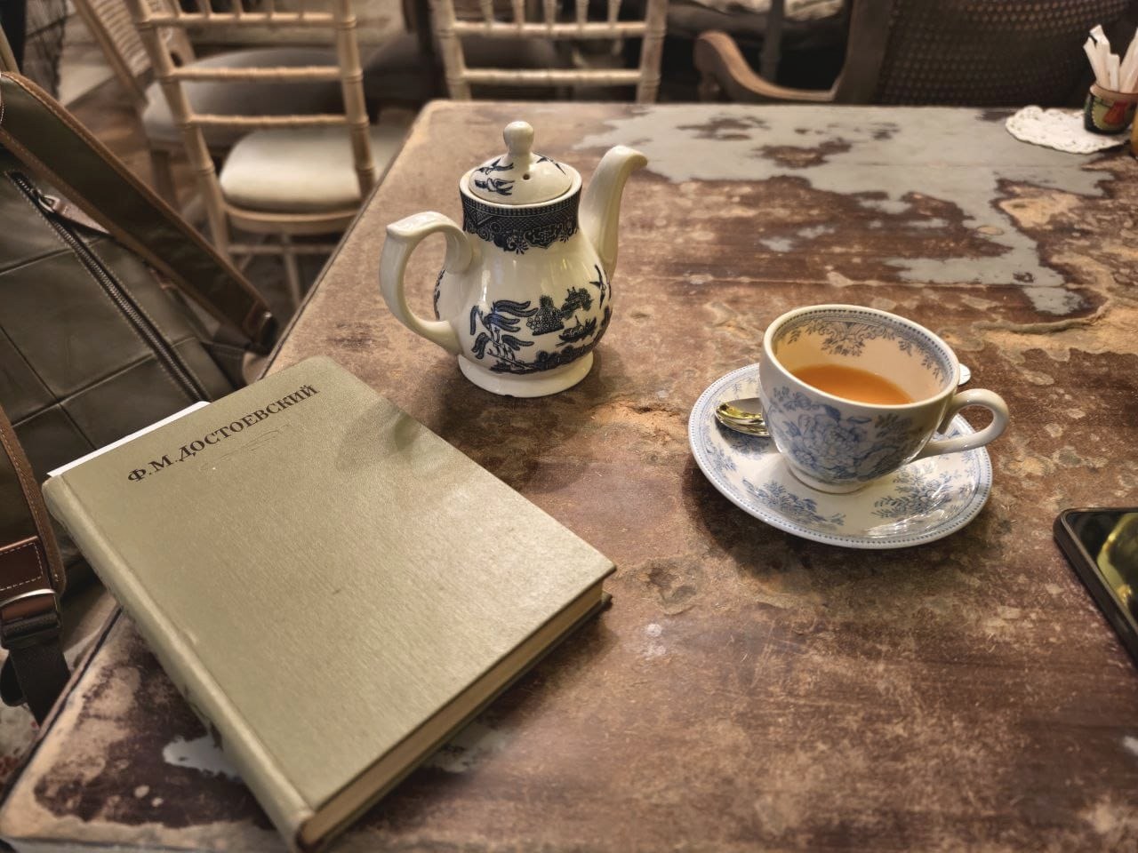 A volume of Dostoevsky beside a pot of tea on a worn table