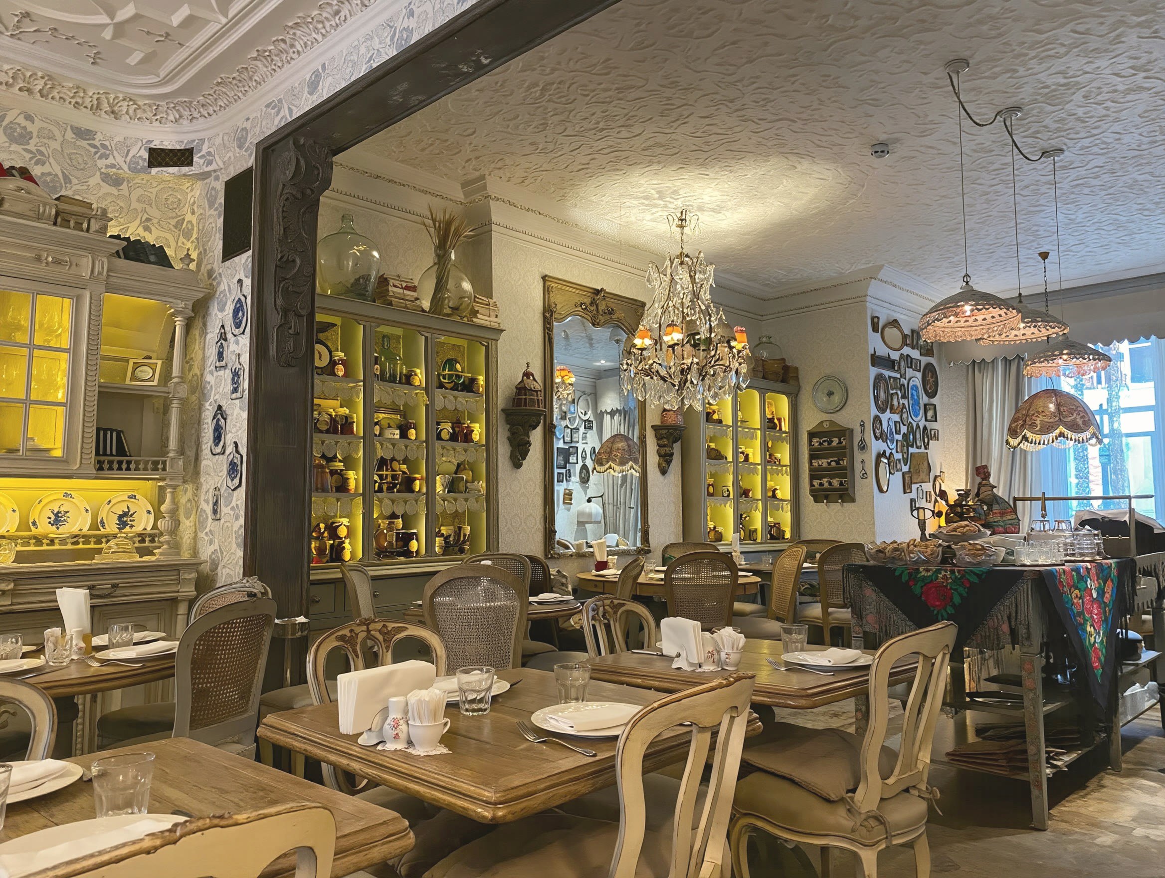 The daylight dining room — chandeliers, glowing cabinets and the samovar table