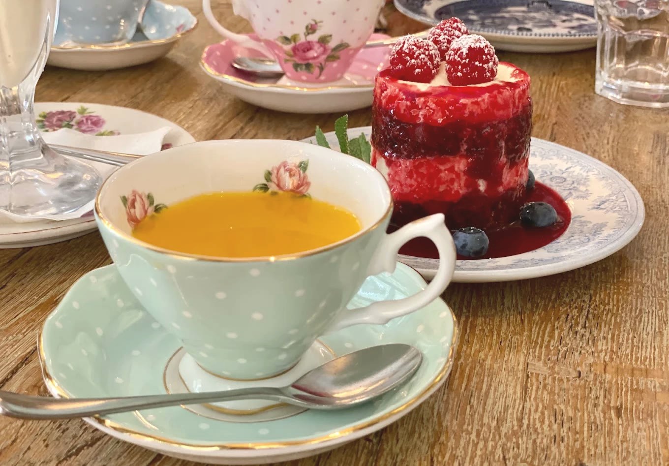 Afternoon tea — polka-dot cups, a berry cake and mixed vintage china